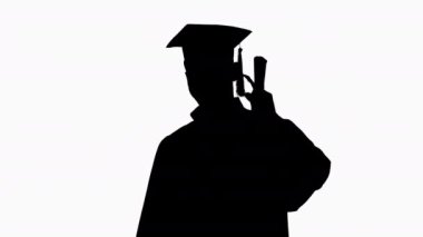 Siluet Genç erkek gülümseyen mezun baş parmağını gösteriyor.