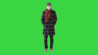 Korunma maskesi takmış İngiliz stili bir adam yeşil ekran, Chroma Key 'e bakıyor..