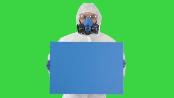 Männlicher Arzt in Schutzkleidung hält leeres Banner auf einem Green Screen, Chroma Key. — Stockvideo