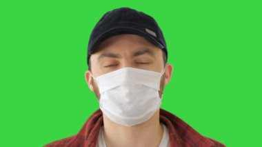 Korumalı sağlık maskesi takan Amerikalı çiftçi yeşil ekran, Chroma Key 'e bakıyor..