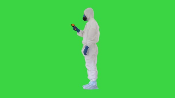 Lekarz noszący odzież ochronną za pomocą termometru na czole w podczerwieni do sprawdzania temperatury ciała pod kątem objawów wirusowych na zielonym ekranie, Chroma Key. — Wideo stockowe