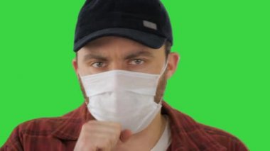 Tıbbi maskeli Amerikalı çiftçi yeşil ekranda öksürüyor, Chroma Key.