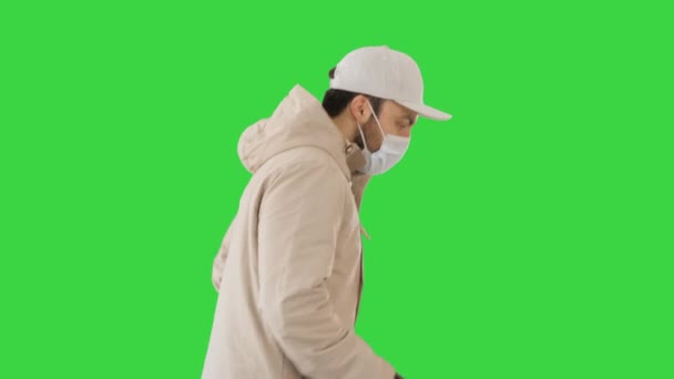 Volwassen man in jas en medisch masker draait op een groen scherm, Chroma Key. — Stockvideo