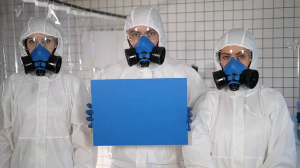 Lab scientists in safety suits holding empty board.