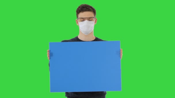 Hombre joven con máscara médica mostrando y mostrando pancarta en una pantalla verde, Chroma Key . — Vídeo de stock