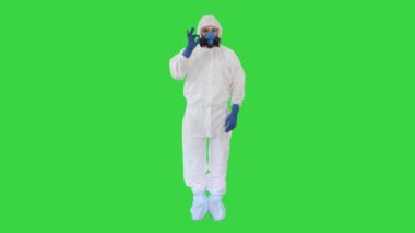 Koruyucu koruyucu giysi giyen doktor yeşil ekran Chroma Key 'de işaret ve başparmağına kadar gösteriyor..