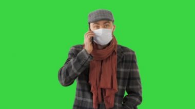 Yeşil Ekran 'da yürürken ve konuşurken koruyucu maskeli şık bir erkek, Chroma Key..
