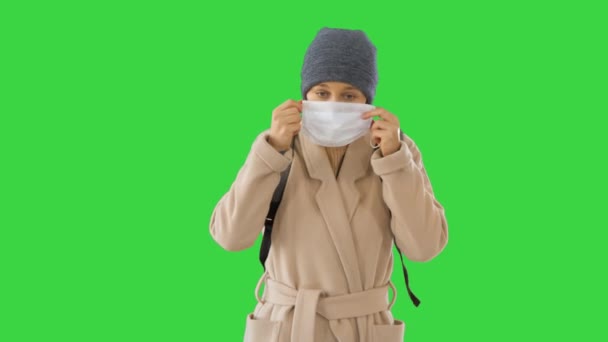 Blonde Frau beim Gehen und Anlegen von Gesichtsschutz zur Vorbeugung gegen Coronavirus covid 19 auf einem Green Screen, Chroma Key. — Stockvideo