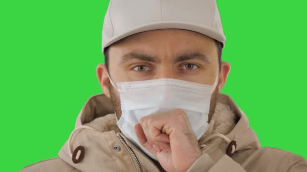 Yeşil ekranda tıbbi maskeli sıradan bir adam öksürüyor, Chroma Key.. — Stok video