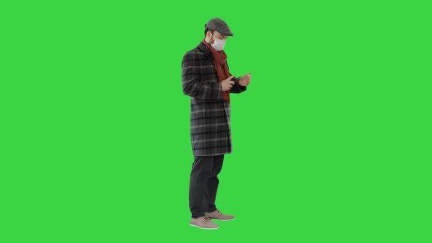 크로마 키그린 스크린 (Green Screen) 에서 손을 위해 소독제를 사용하여 보호 마스크를 쓴 남자. — 비디오