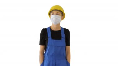 Sarı şapkalı ve tıbbi maskeli genç bir kadın beyaz arka planda yürüyor..