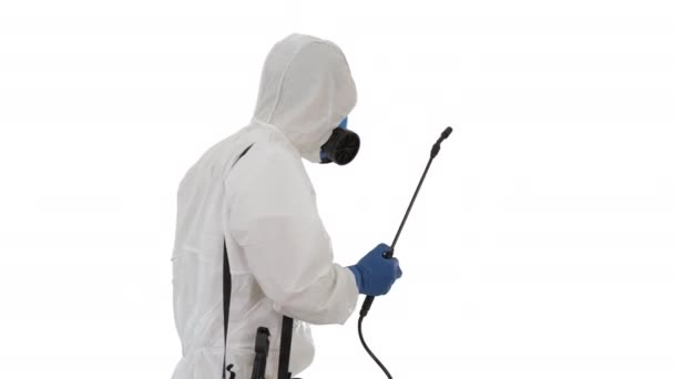 Man in een hazmat pak wandelen en spuiten met een desinfectiemiddel op witte achtergrond. — Stockvideo