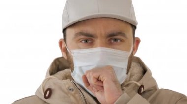 Beyaz arka planda tıbbi maskeli sıradan bir adam öksürüyor..