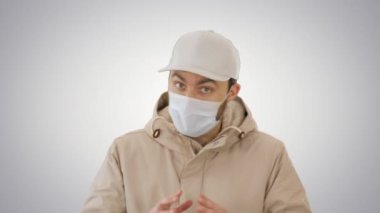 Coronavirus koruması koruyucu maske takan genç hippi arka planda kameraya konuşuyor..