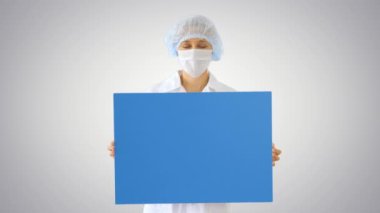 Maskeli kadın doktor, arka planda boş bir tahta tutuyor..