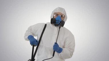Kişisel koruyucu giysi, eldiven, maske ve yüz kalkanı giyen bir adam değişken arka planda dezenfekte etmeye hazır..