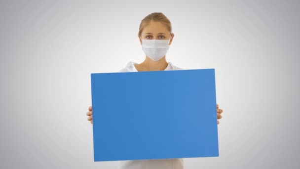 Hermosa mujer de negocios en máscara de protección sosteniendo tablero en blanco sobre fondo degradado . — Vídeos de Stock