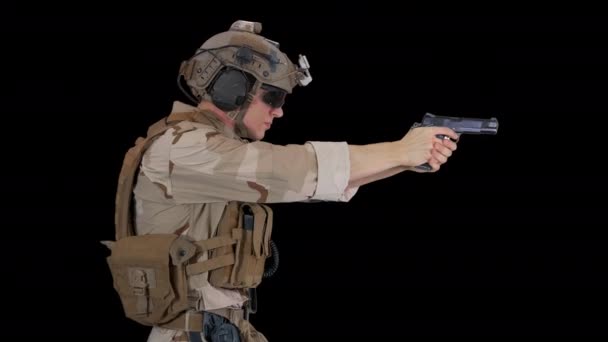 Een soldaat met een helm op z 'n hoofd... lopend en schietend met een handwapen, Alpha Channel. — Stockvideo