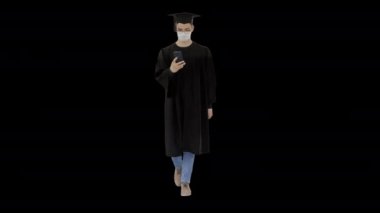 Mezuniyet kıyafetli genç adam, Alpha Channel 'da, akıllı telefon kullanarak tıbbi maske takıyor.