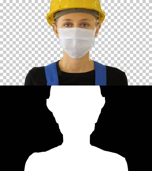 Жінка будівельник в шоломі безпеки кладе медичну маску — стокове фото