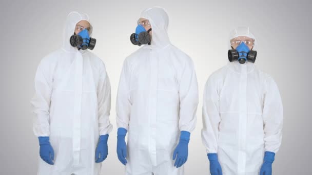 Ομάδα επιστημόνων ή ιατρών με προστατευτικές στολές έτοιμες για εργασία που διασχίζουν τα χέρια σε βαθμιδωτό φόντο. — Αρχείο Βίντεο