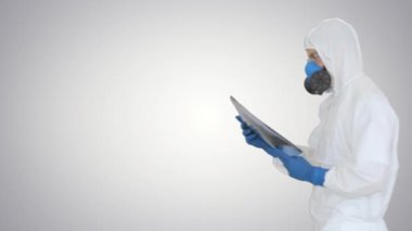 Koruyucu kıyafetli bir doktor, arka planda röntgen görüntüsüyle içeri giriyor..