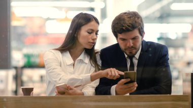 Teknoloji ve insanlar kavramı - akıllı telefonları olan iş çifti telefonlarında yeni uygulamalar deniyor.