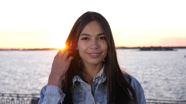 Portrait de jeune femme souriante attrayante regardant la caméra au coucher du soleil. — Photo