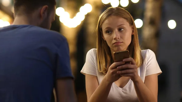 无聊的少女在约会中使用电话。夫妇花时间在手机上滚动网页. — 图库照片