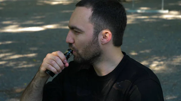 Jeune homme vaporisant une cigarette électronique pour la première fois. être agacé par la fumée. — Photo