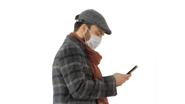 Hombre con estilo en la máscara médica caminando y utilizando el teléfono inteligente en whi — Foto de Stock