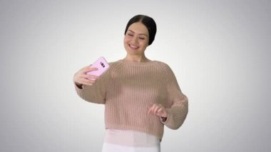 Sıradan esmer kız gülümsüyor. Gradyan arka planda telefonda selfie çekiyor..