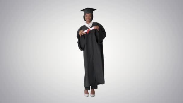 Happy afro graduating female student dancing on gradient background. — Stock Video