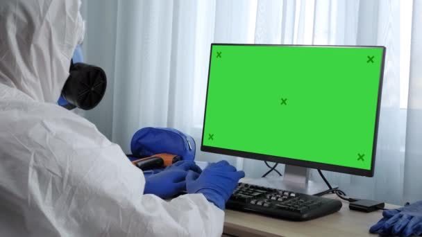 Ώριμος γιατρός με προστατευτική στολή που εργάζεται στον υπολογιστή. Πράσινη οθόνη mock-up οθόνη. — Αρχείο Βίντεο