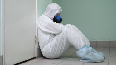 Tehlikeli takım elbiseli yorgun doktor yerde oturuyor ve uyuyor. O