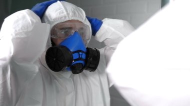 Korkmuş ve şok olmuş biyo-kostümlü bir doktor ya da virolog.