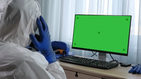 Científico en traje de protección viendo información sobre la computadora y havin — Foto de Stock