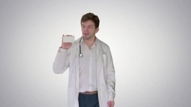 Yürüyen Erkek Doktor gradyan arka planda boş beyaz hap kutusu gösteriyor.