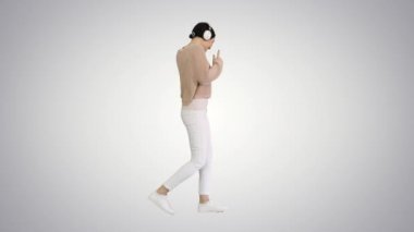 Mutlu duygusal kız beyaz kulaklıkla müzik dinliyor ve değişken arka planda yürüyor..