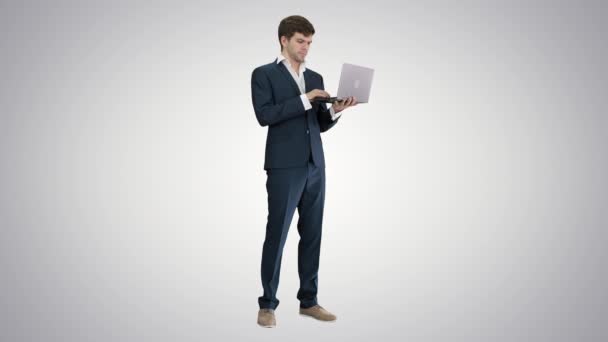 Muy emocionado hombre elegante en traje de pie con el ordenador portátil en las manos Concepto de éxito en el fondo de gradiente . — Vídeo de stock
