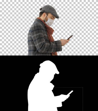 Tıbbi maskeli şık bir adam yürüyor ve akıllı telefon kullanıyor, Alpha.