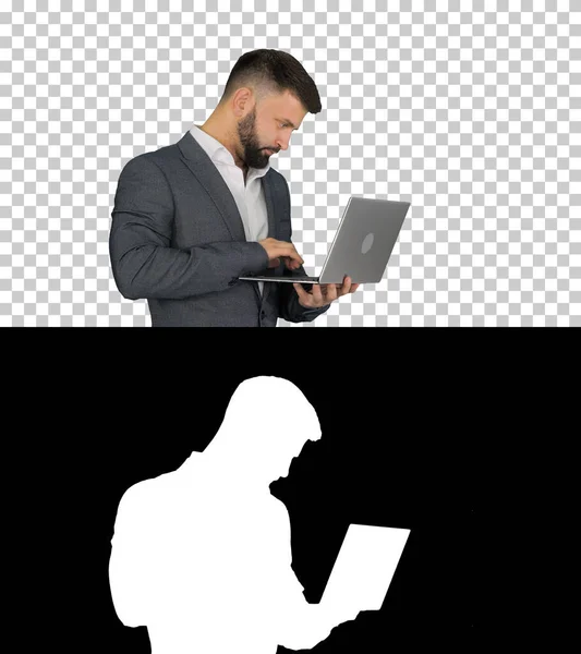 Biały mężczyzna piszący na stojąco na laptopie, kanał Alfa — Zdjęcie stockowe