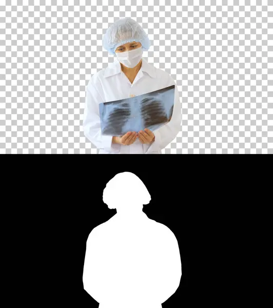 Жіночий лікар у медичній масці дивиться на рентгенівський знімок Альфа. — стокове фото
