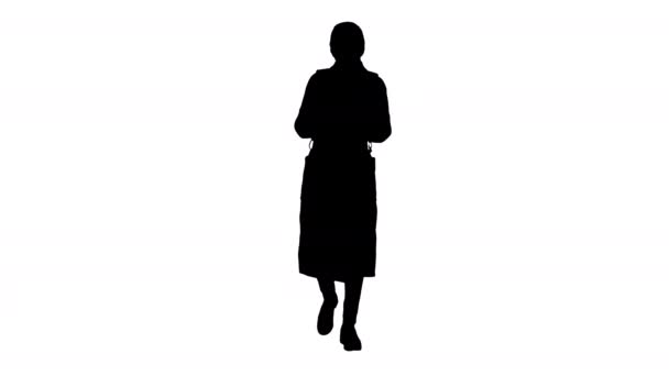 Silhouette Femme vêtue d'un manteau portant un masque médical en utilisant le téléphone et la marche . — Video