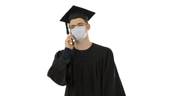 Giovane studente laureato fare una chiamata con smartphone con maschera medica su sfondo bianco . — Foto Stock