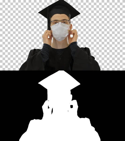 Young man with graduation gown in medical mask, Alpha Channel