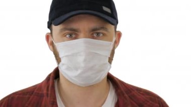 Siyah beyzbol şapkalı, beyaz arka planda yüzünde tıbbi maske olan bir adam..