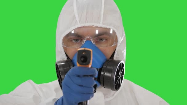 Koruyucu biyolojik tehlike kıyafetli doktor, yeşil ekran, Chroma Key 'deki 19 numaralı kontrol noktasında sıcaklığınızı ölçmek için lazer termometreyi gösteriyor.. — Stok video