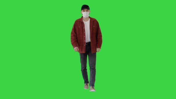 Mann in lässigem Hemd und Mütze mit medizinischer Maske auf einem Green Screen, Chroma Key. — Stockvideo