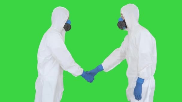 Лікарі або науковці в костюмах хазамату зустрічаються і тиснуть один одному руки на зеленому скринінгу, Chroma Key. — стокове відео